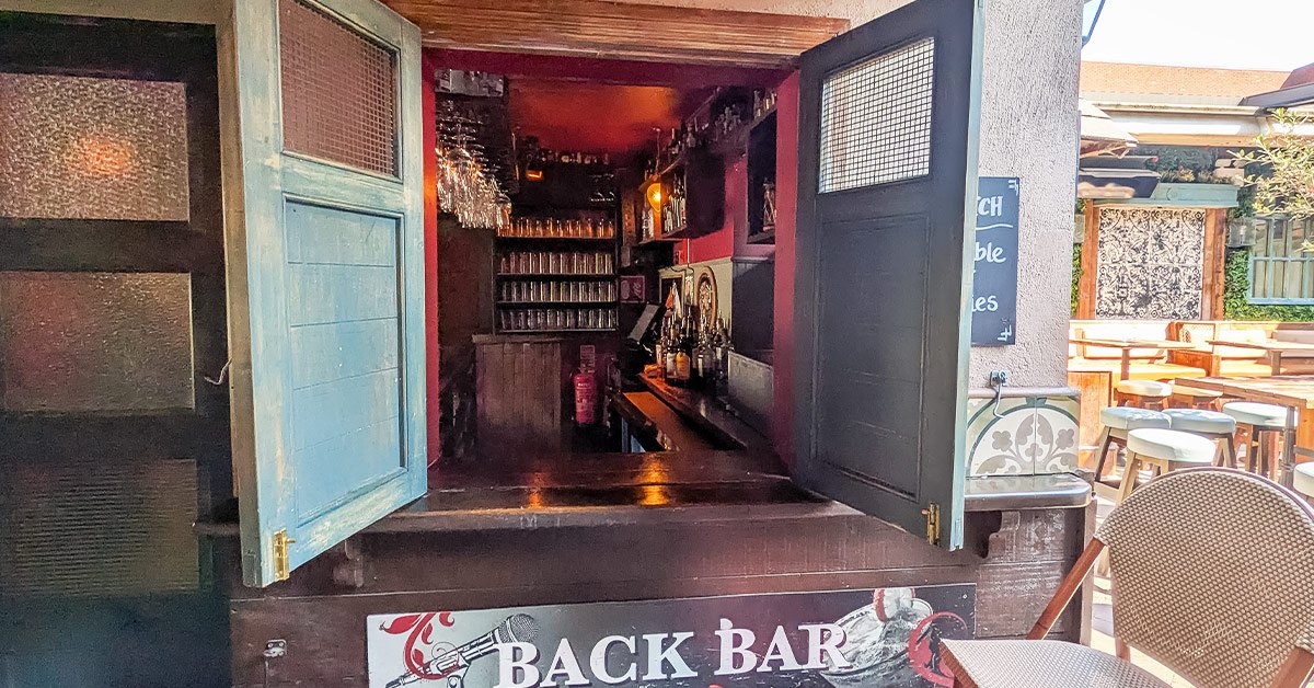 Open doors leading into The Back Bar from the garden, with The Back Bar sign on the step