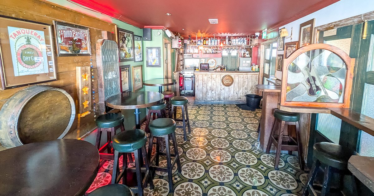 The Back Bar with patterned tiles, a mirrored wall and tall tables beside the counter
