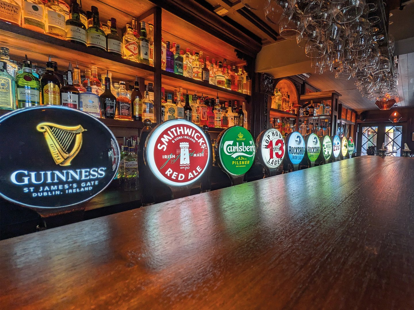The long polished counter in The Kavern, with taps, bottles and hanging glasses