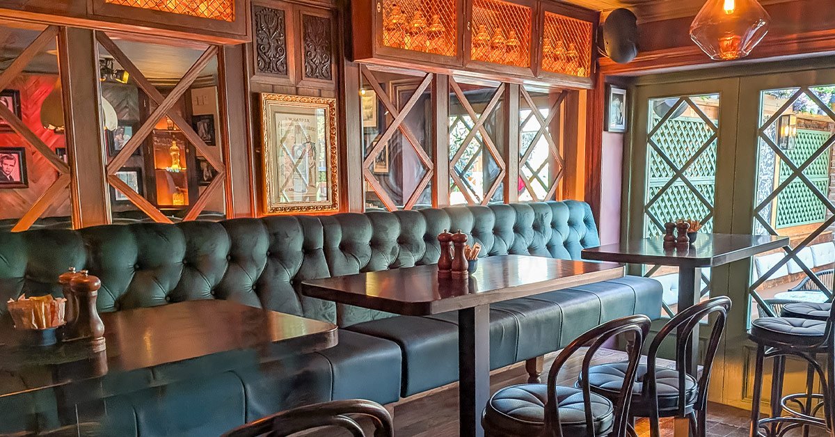 Deep green upholstered couches and tables beside whiskey displays in The Kavern