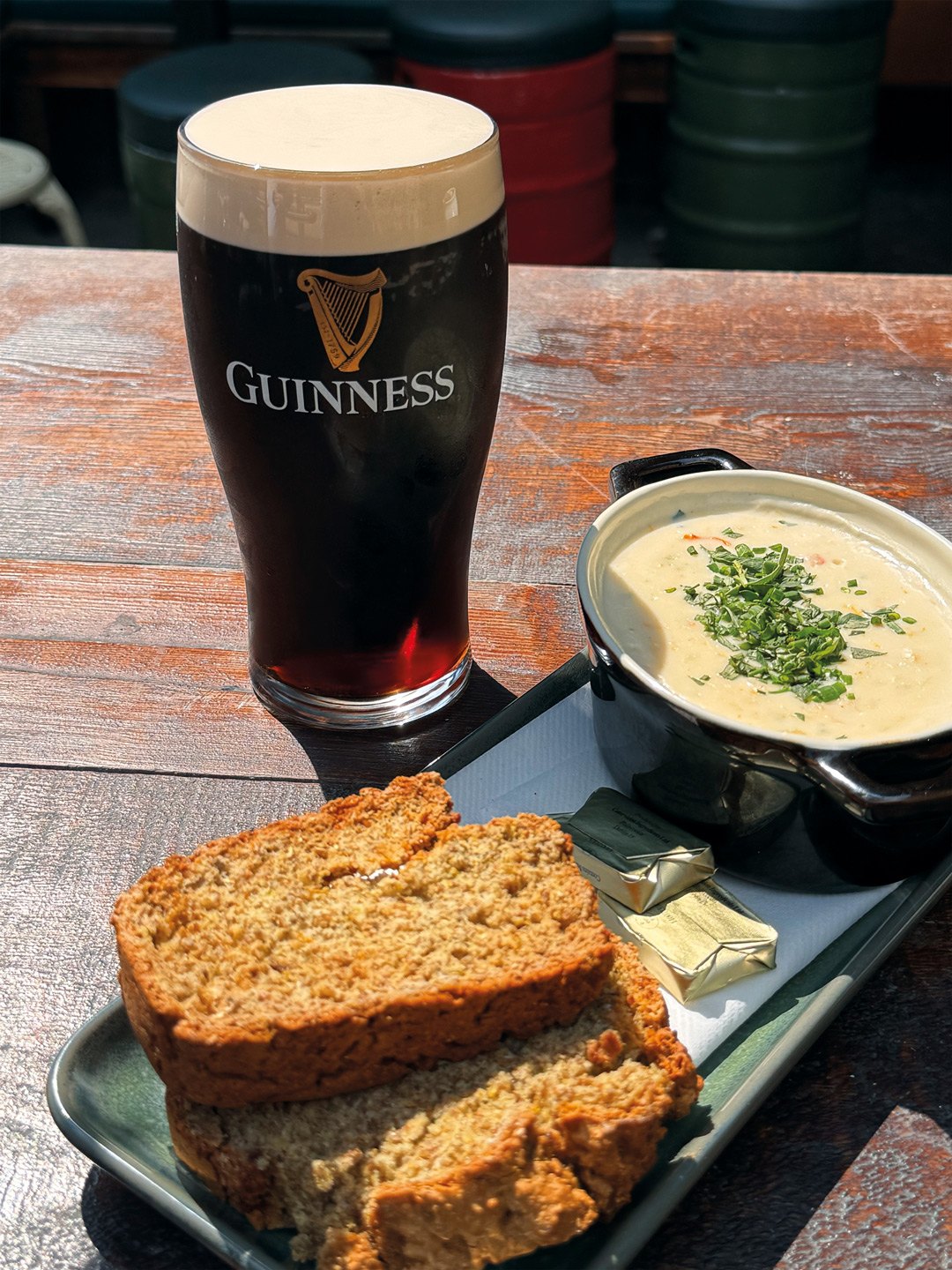 A pint of Guinness, a bowl of soup and homemade brown bread on a table in the beer garden